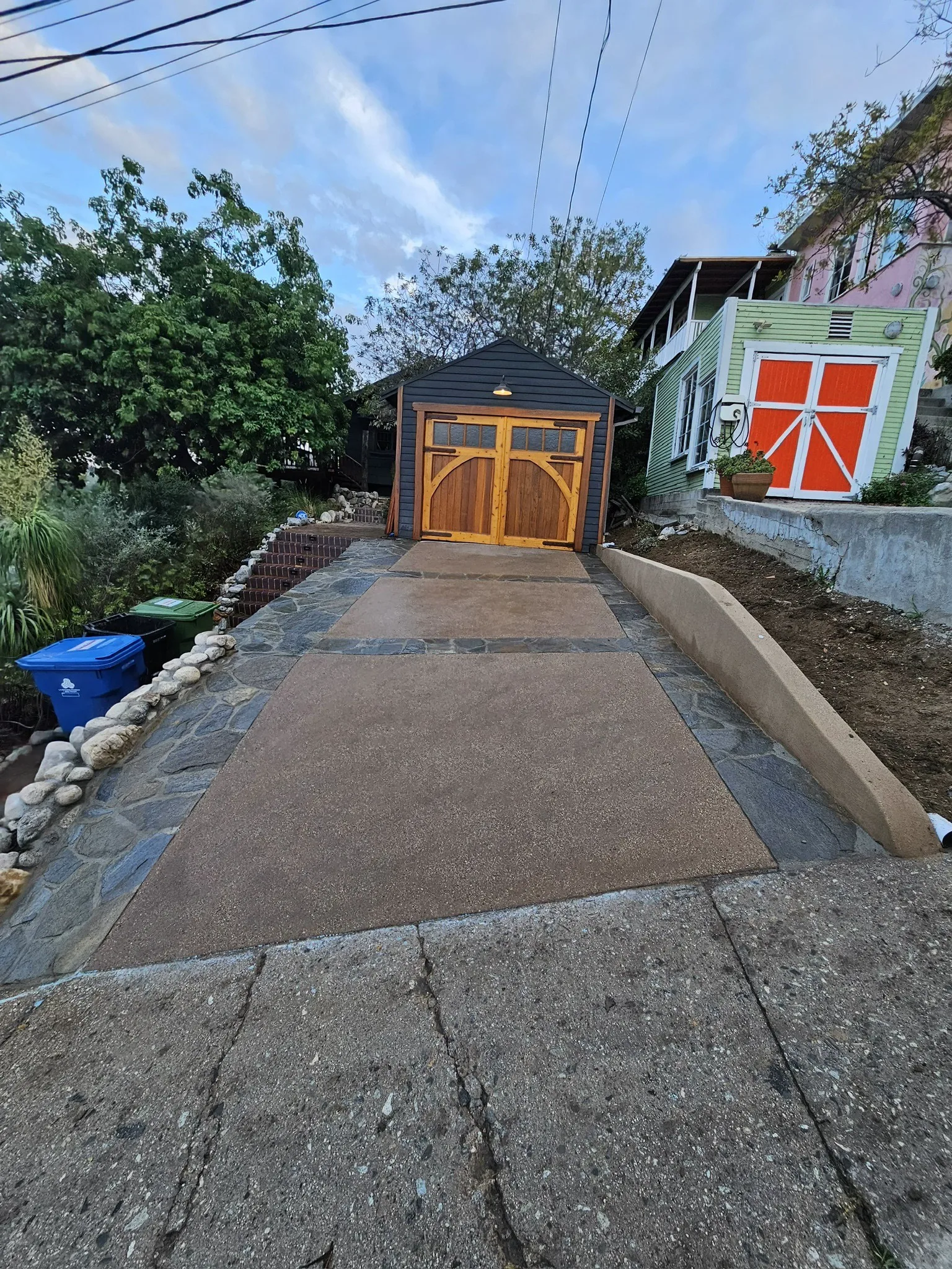 Concrete driveway bordered by a river rock wall
