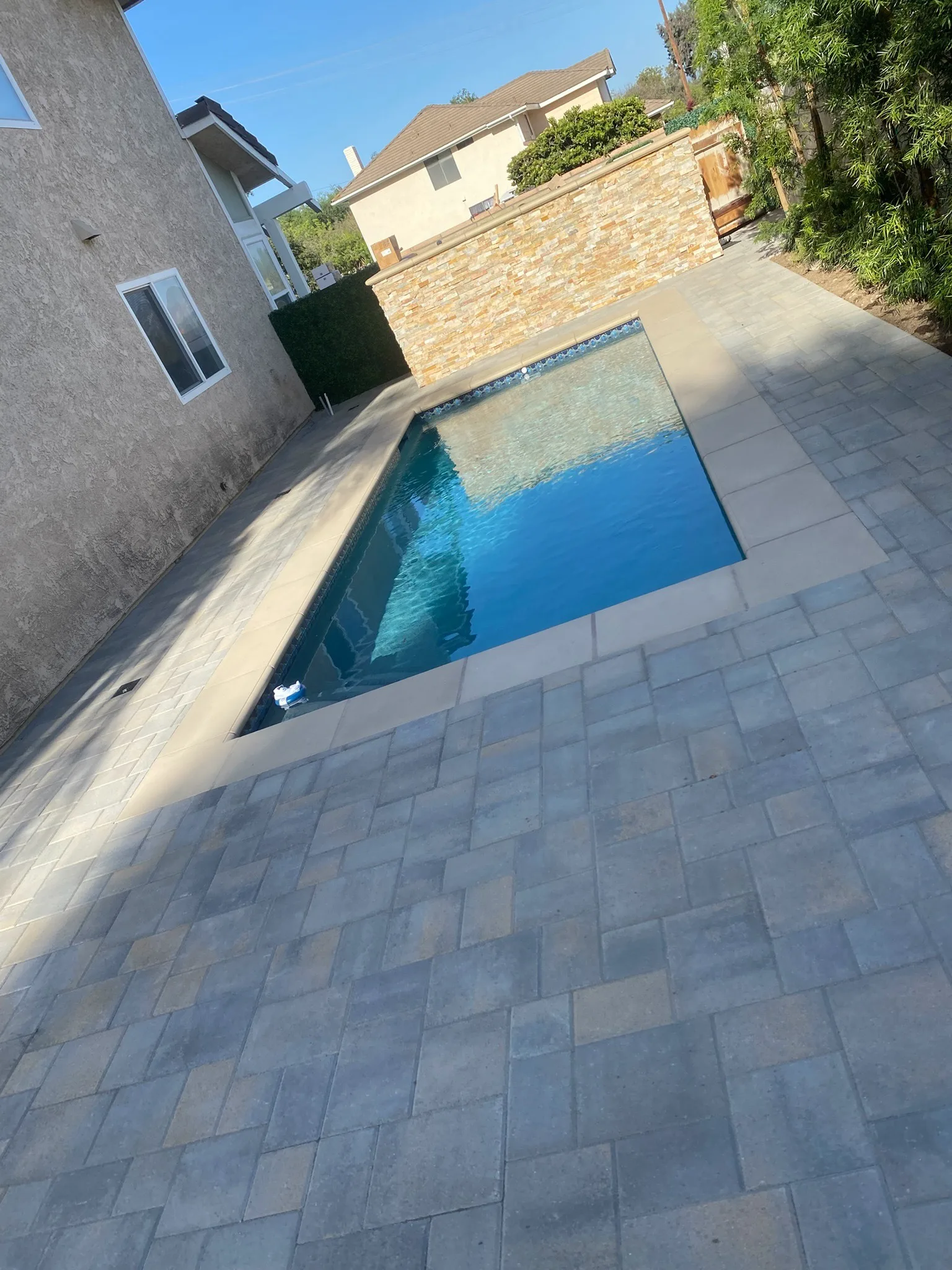 Gray paver pool deck alongside a backyard swimming pool