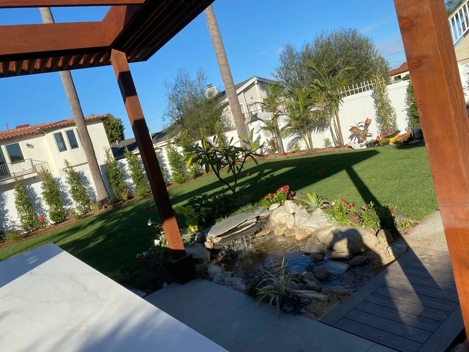 Backyard pergola beside a water feature and lawn