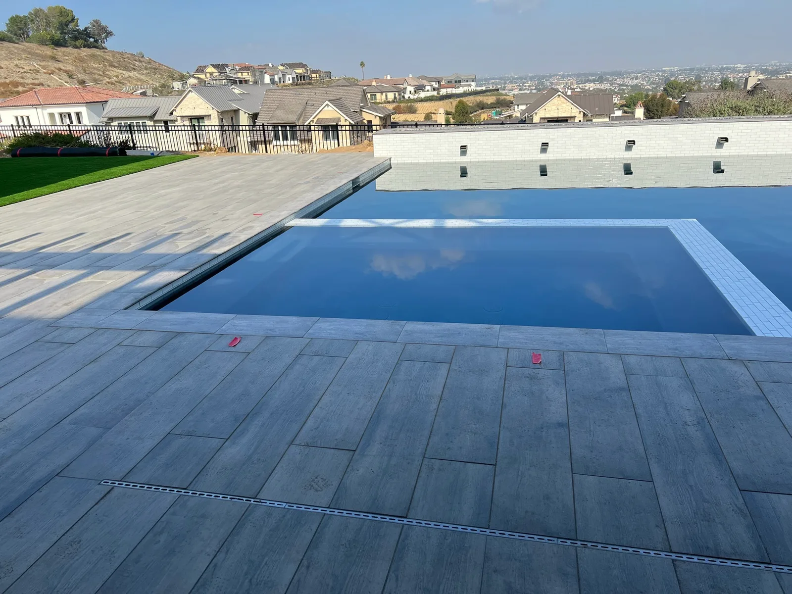 Wood-look porcelain tile deck around a modern pool