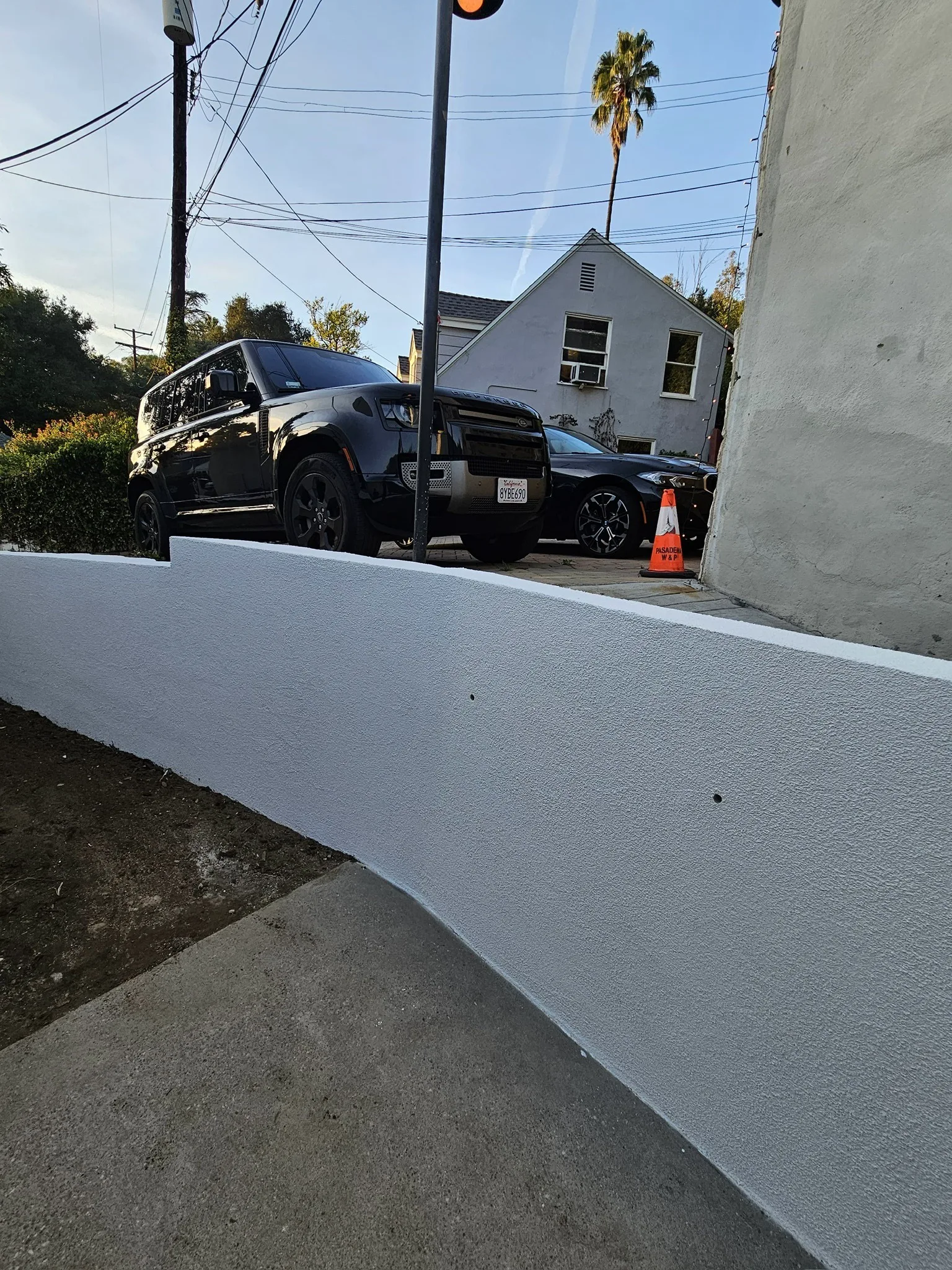 Curved white retaining wall along a driveway