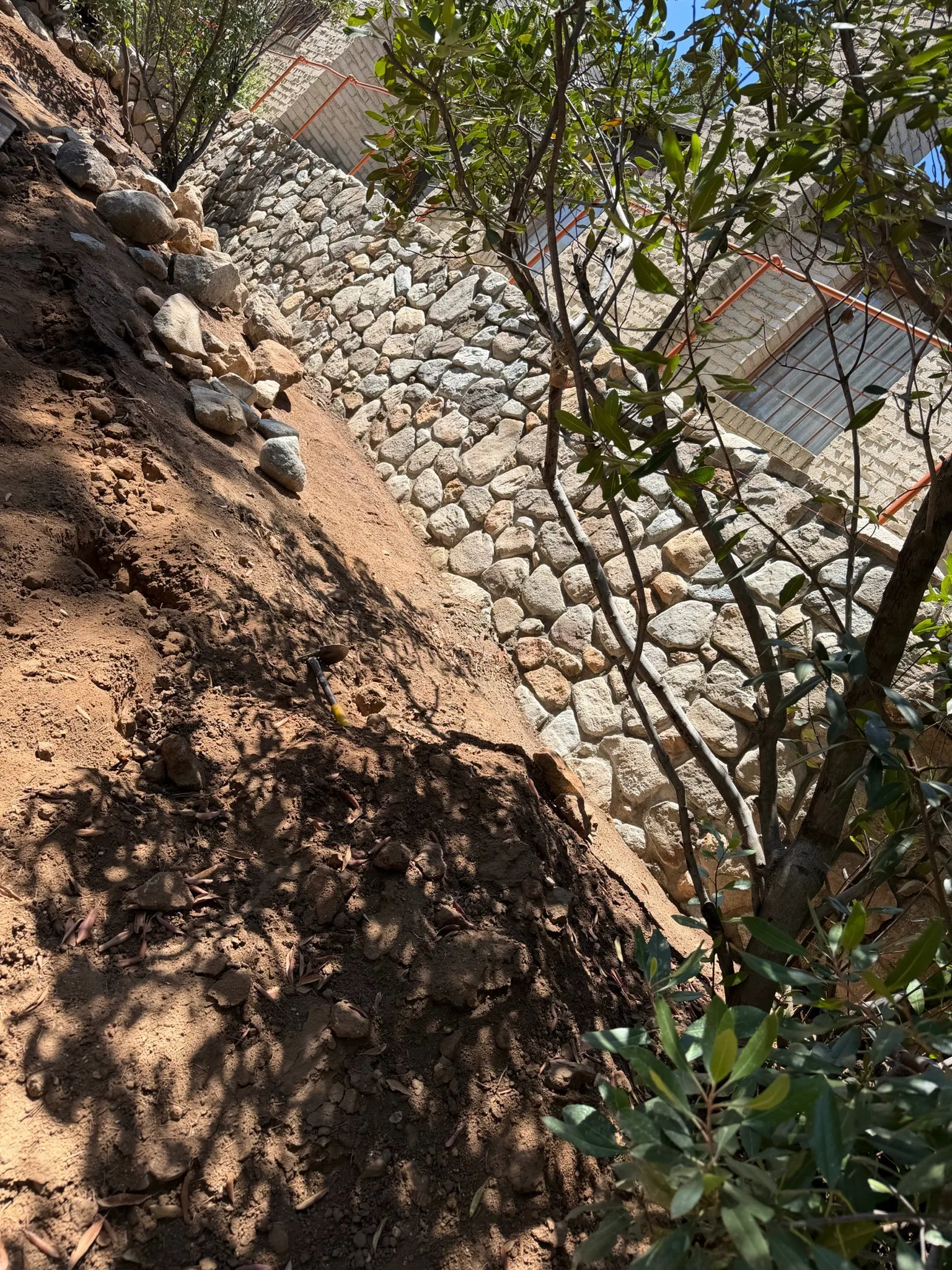 River rock wall being rebuilt on a hillside