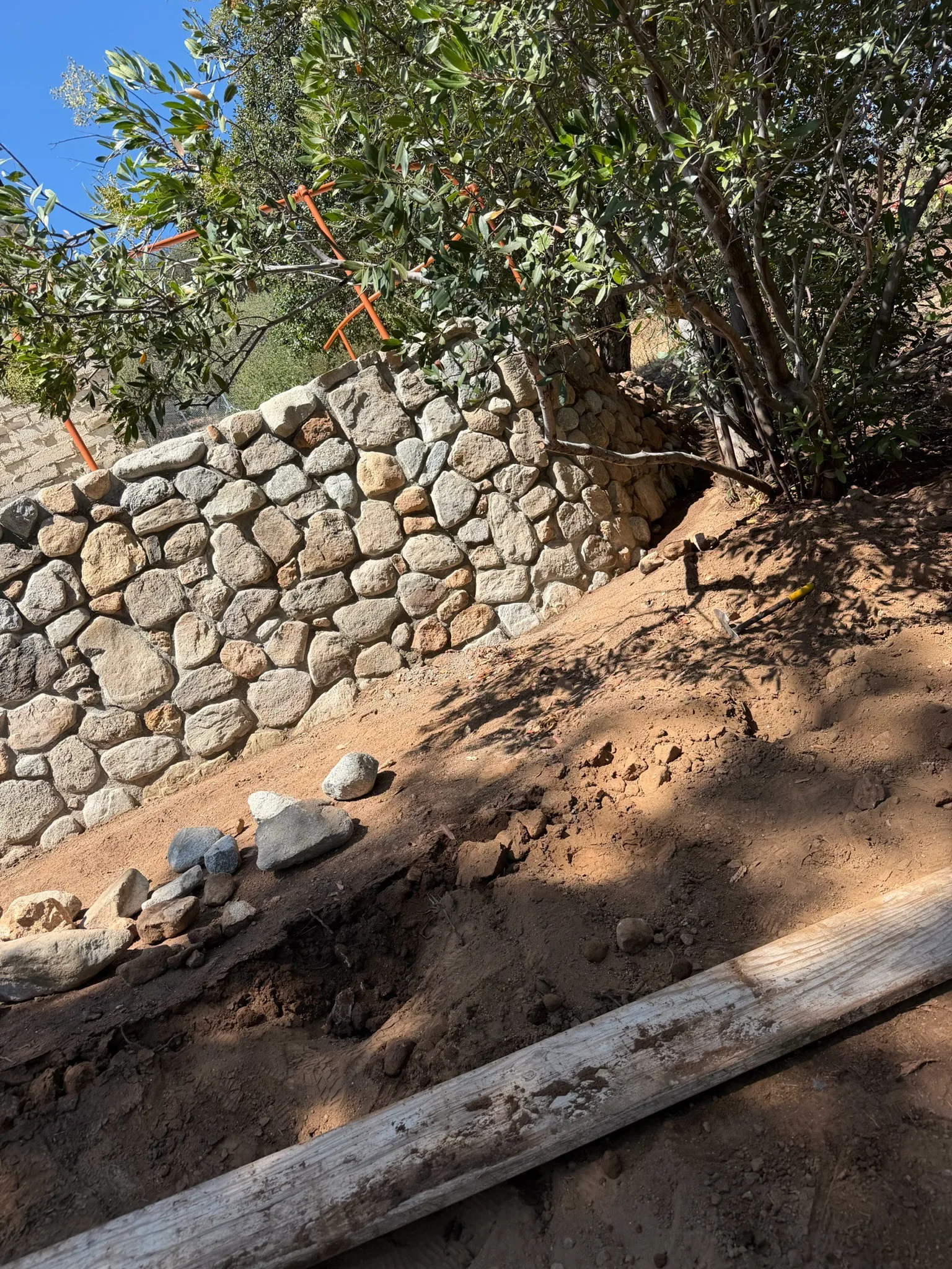 River rock wall being rebuilt into a hillside