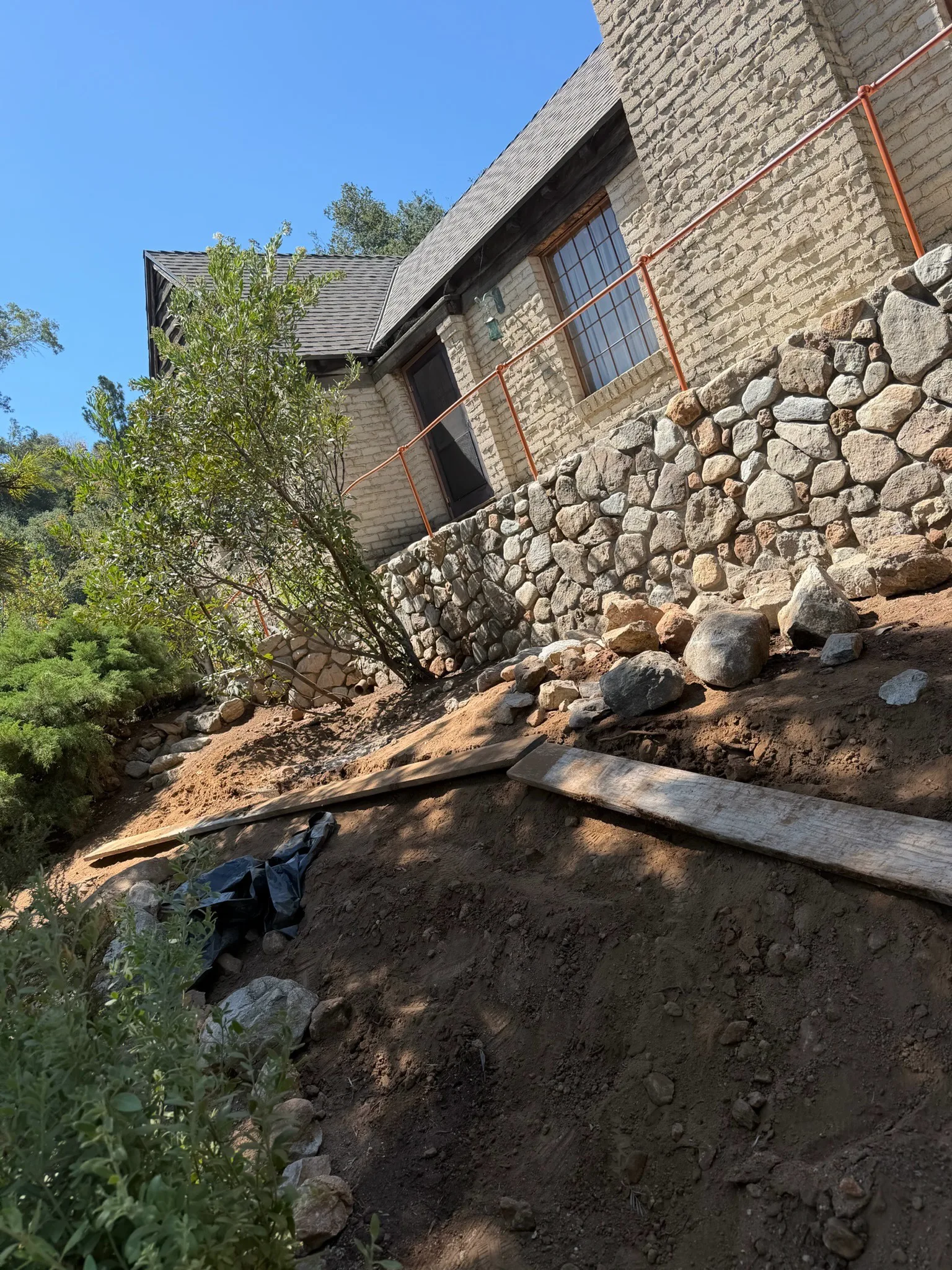 Natural stone wall running below a hillside home